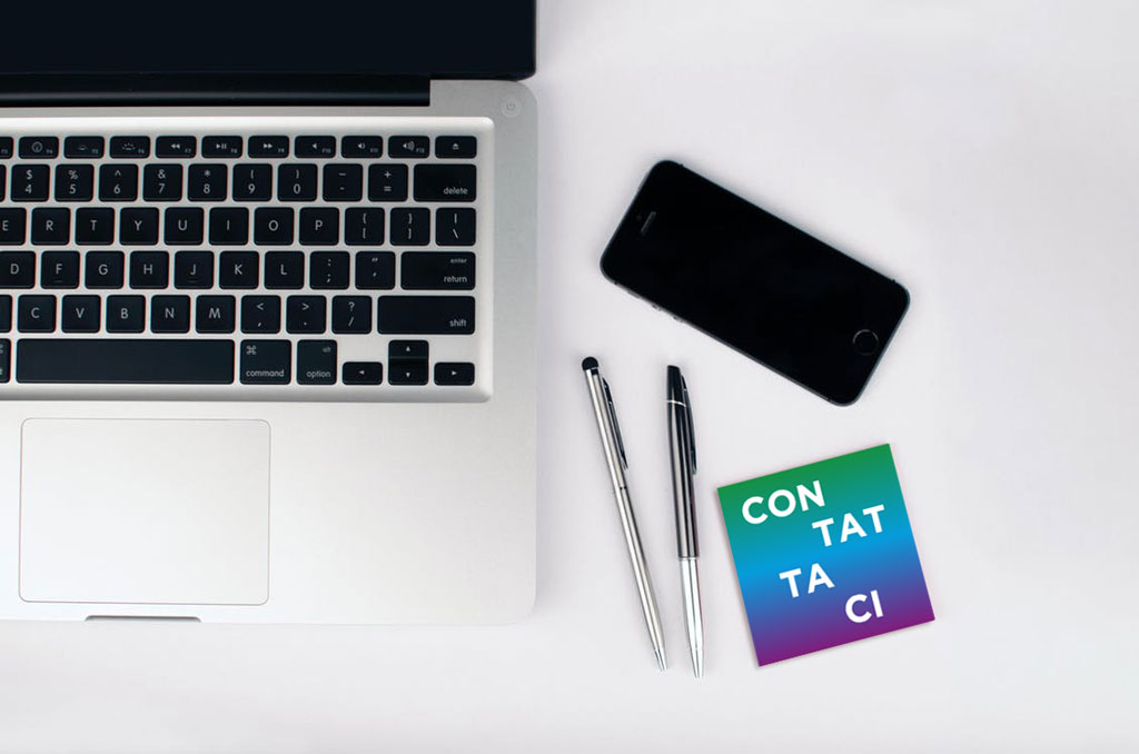 Scrivania con Computer, smartphone, penne da scrivere e biglietto da visita con scritto Contattaci